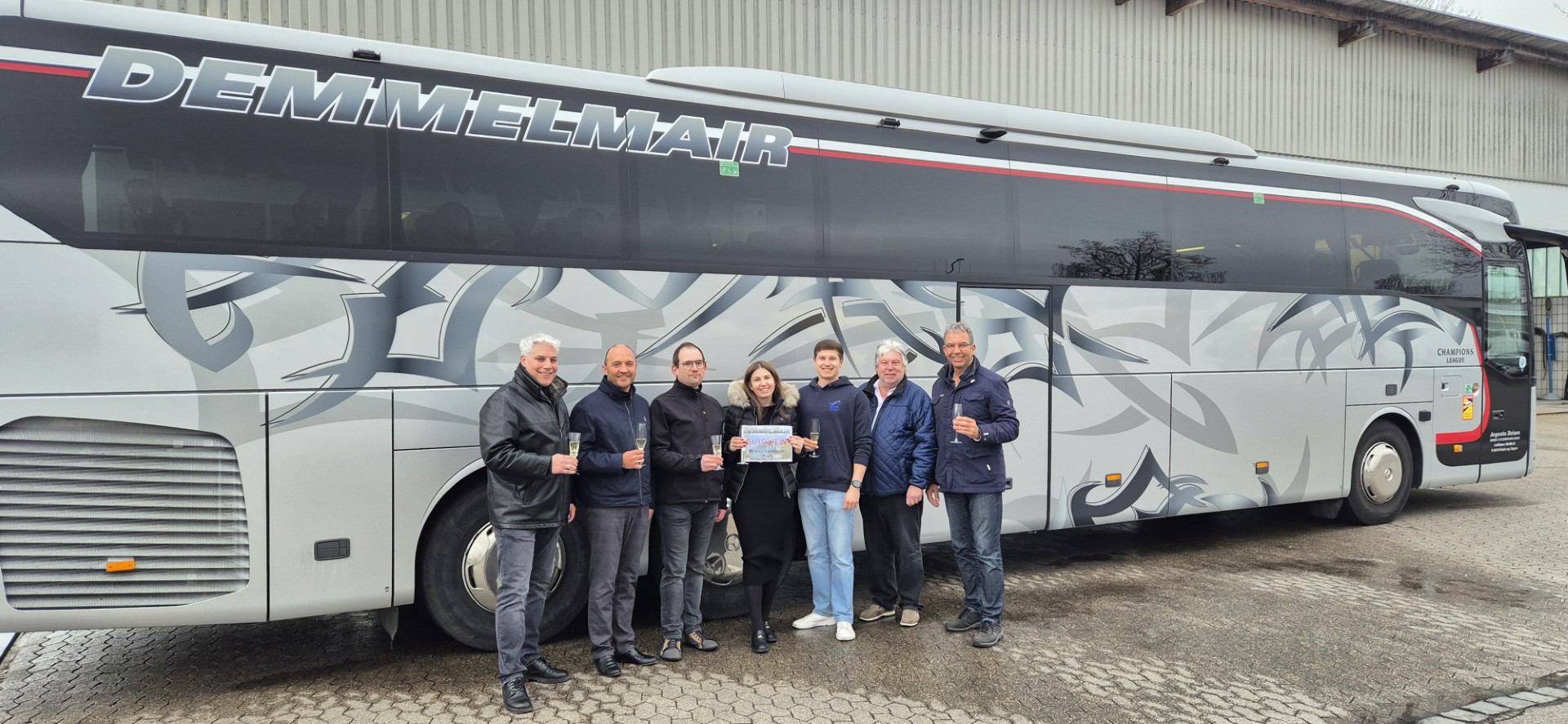 Gewinner und Gewinn-Spender zusammen vor einem Reisebus der Firma Demmemair.