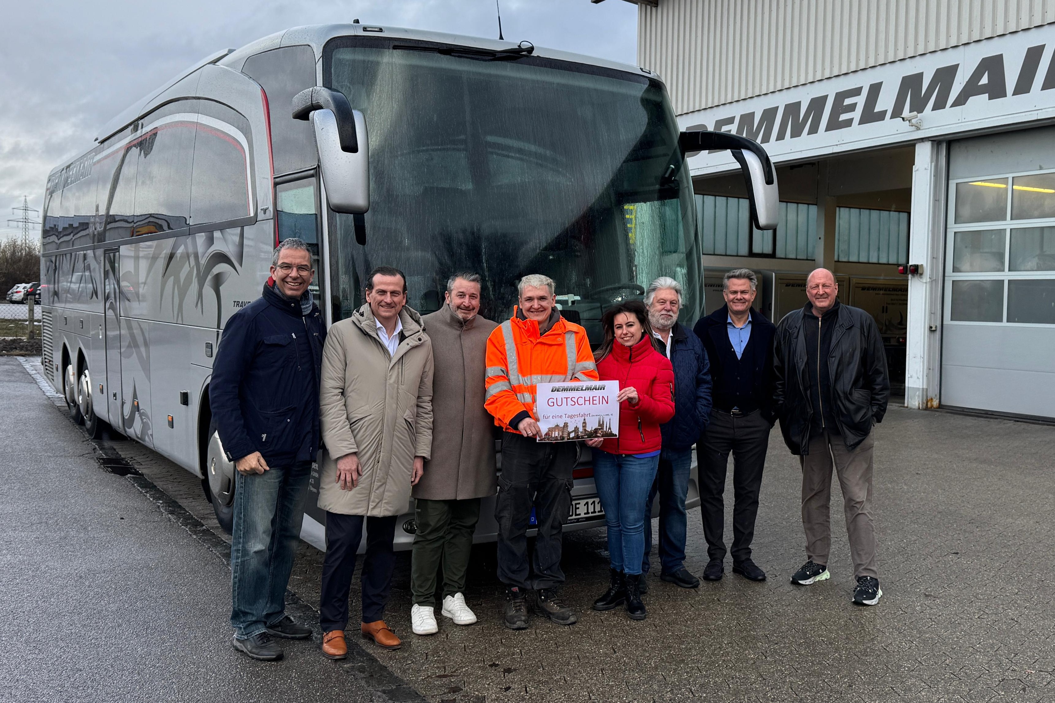 Gewinner und Gewinn-Spender zusammen vor einem Reisebus der Firma Demmemair.